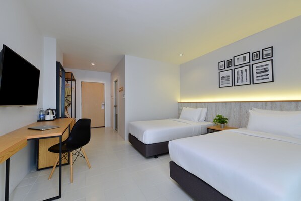 Quarto de hotel com escrivaninha, duas camas, televisão e obras de arte na parede.
