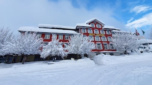 Un bâtiment rouge avec une enseigne indiquant « HÔTEL STERNEN », devant des arbres couverts de neige.