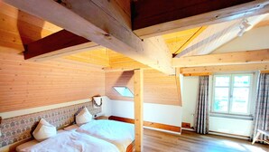 Une chambre à coucher en bois, avec un lit, une table de chevet, une fenêtre avec des rideaux et un plafond en pente.