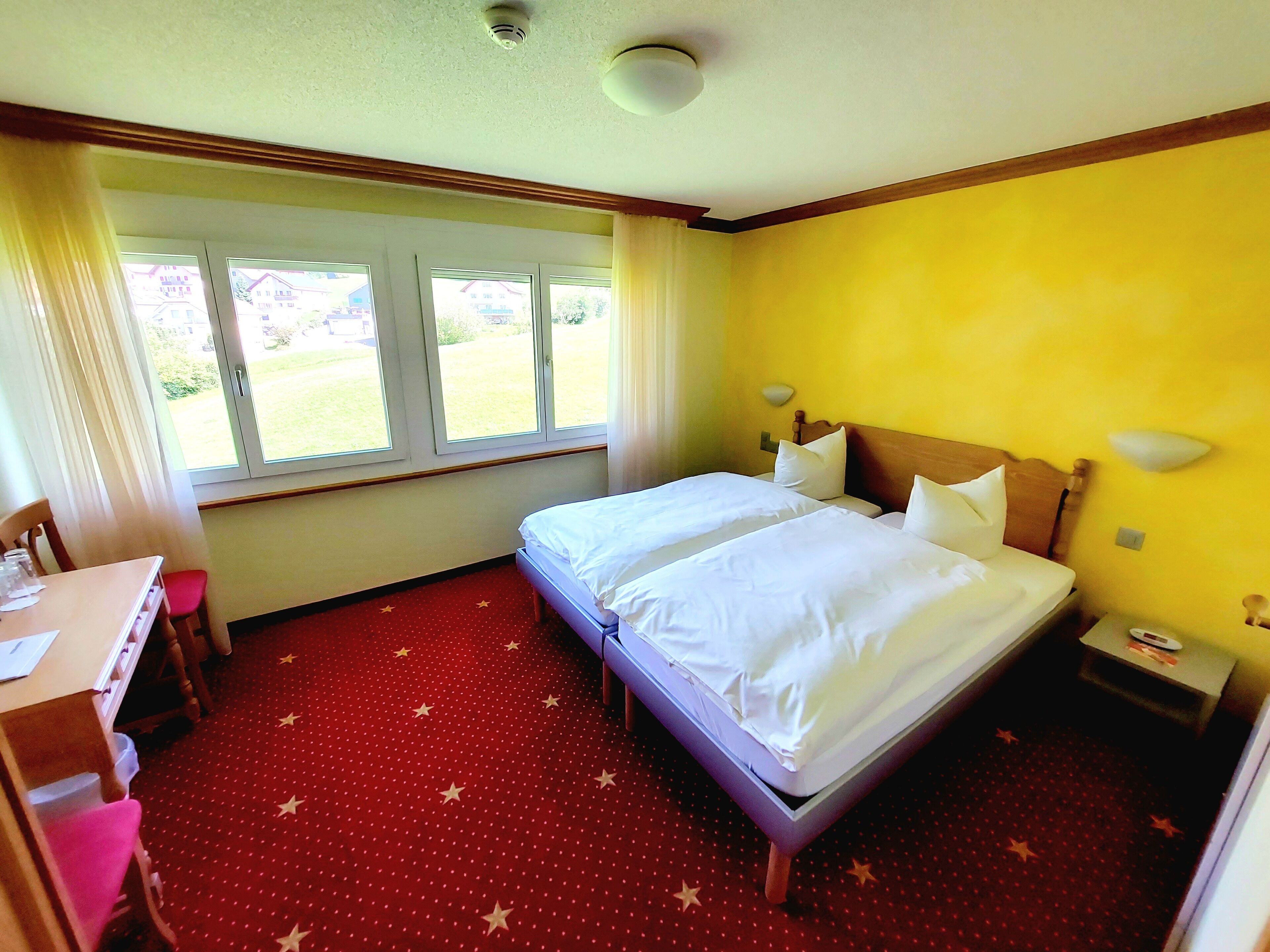 Ein Hotelzimmer mit zwei Betten, einem Schreibtisch und einem Stuhl.