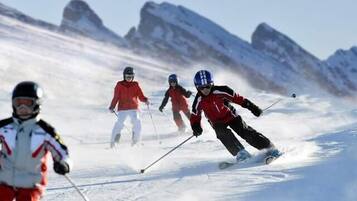 A group of skiers on a snowy slope with mountains in the background.