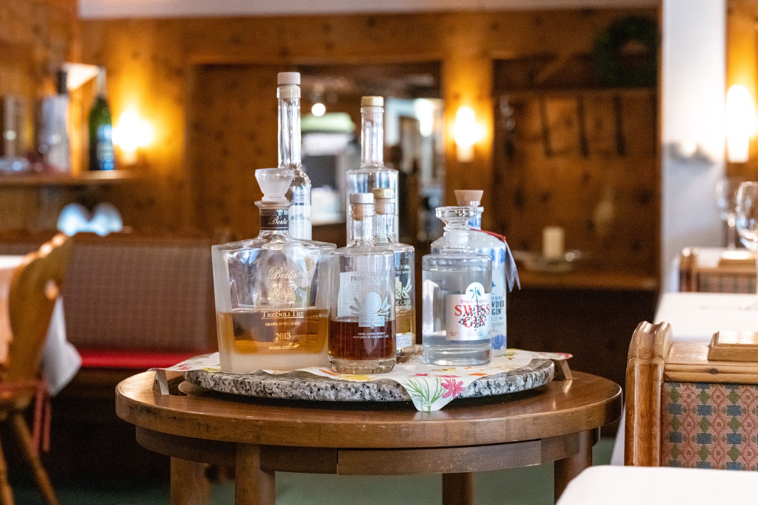 Una zona de bar con una mesa de madera que muestra diferentes botellas y vasos.