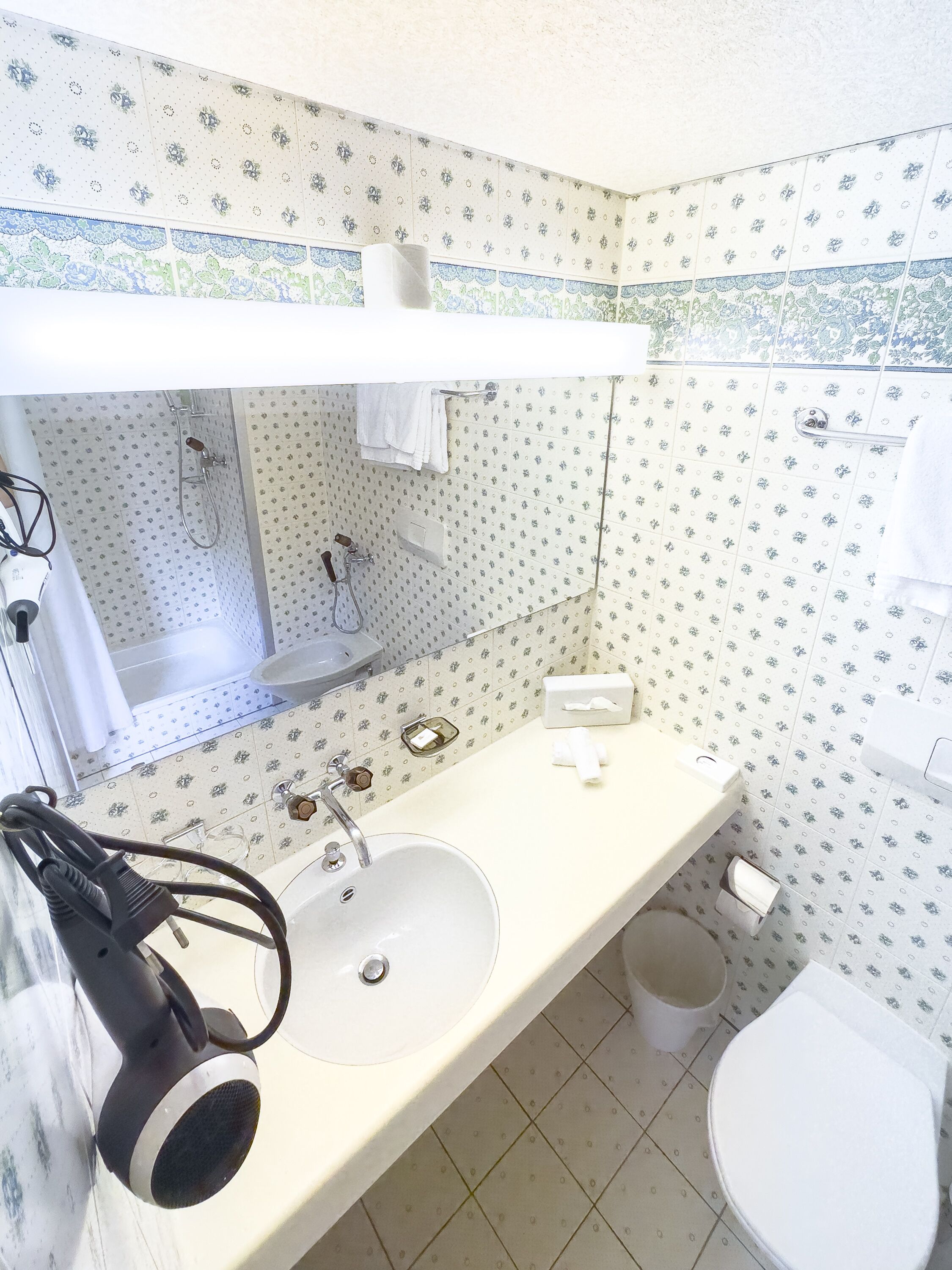 A bathroom with a white sink, a mirror, a towel rack, a shower, and a toilet.