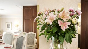 Een eetgedeelte met een tafel voor twee personen, een bloemenvaas en een wandlamp.