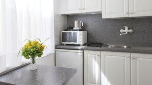 Een moderne keuken met witte kastjes, een granieten aanrecht, een magnetron, een broodrooster en een vaas met gele bloemen op de tafel.