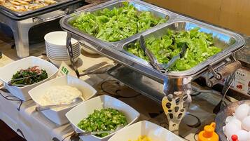 A buffet with various food items including salads, vegetables, and a container of eggs.