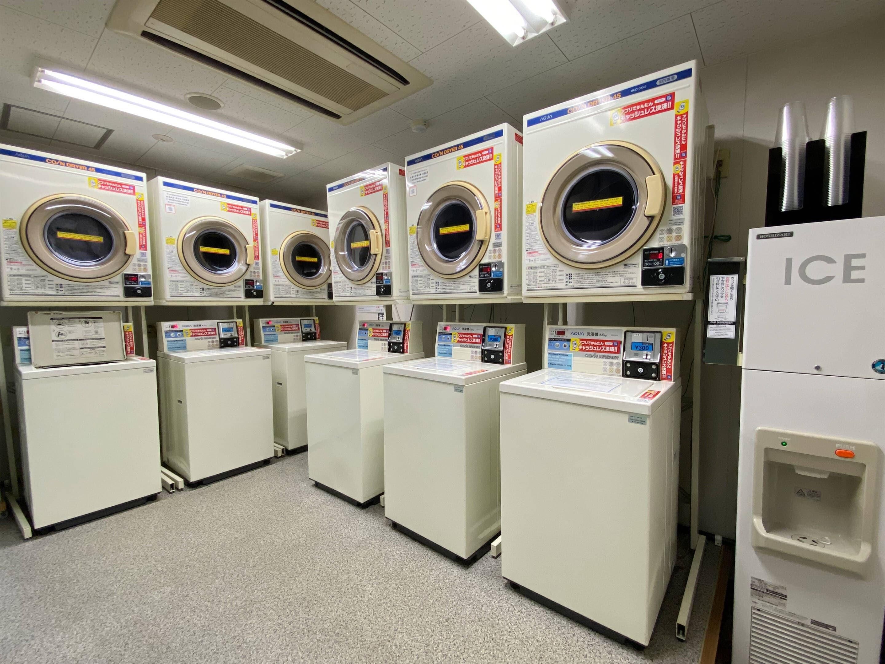 Une laverie équipée de plusieurs machines à laver et de plusieurs séchoirs, dont un appareil de la marque ICE.