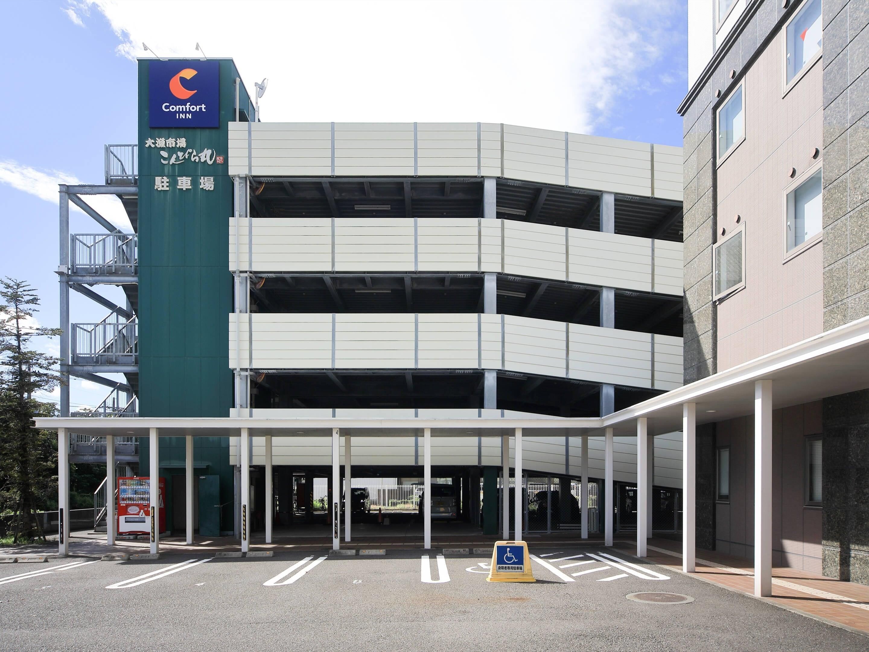 A multi-story parking garage with a Comfort Inn sign, a wheelchair accessibility sign, and a vending machine.