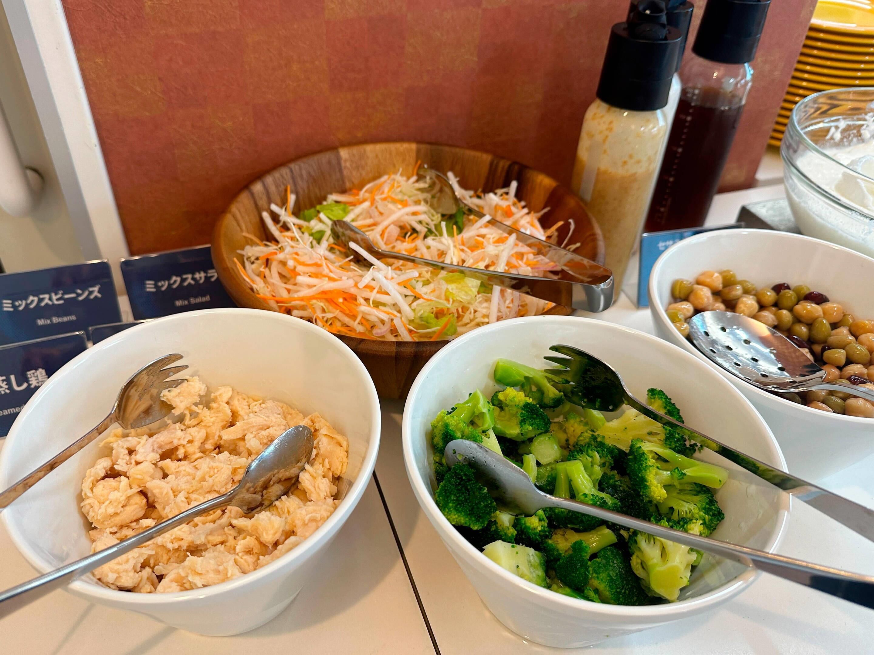 Une table sur laquelle se trouvent des bols remplis de nourriture, notamment un mélange de haricots, de légumes coupés en julienne et de brocolis.