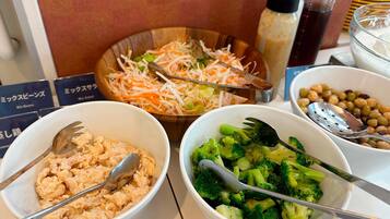 Une table sur laquelle se trouvent des bols remplis de nourriture, notamment un mélange de haricots, de légumes coupés en julienne et de brocolis.