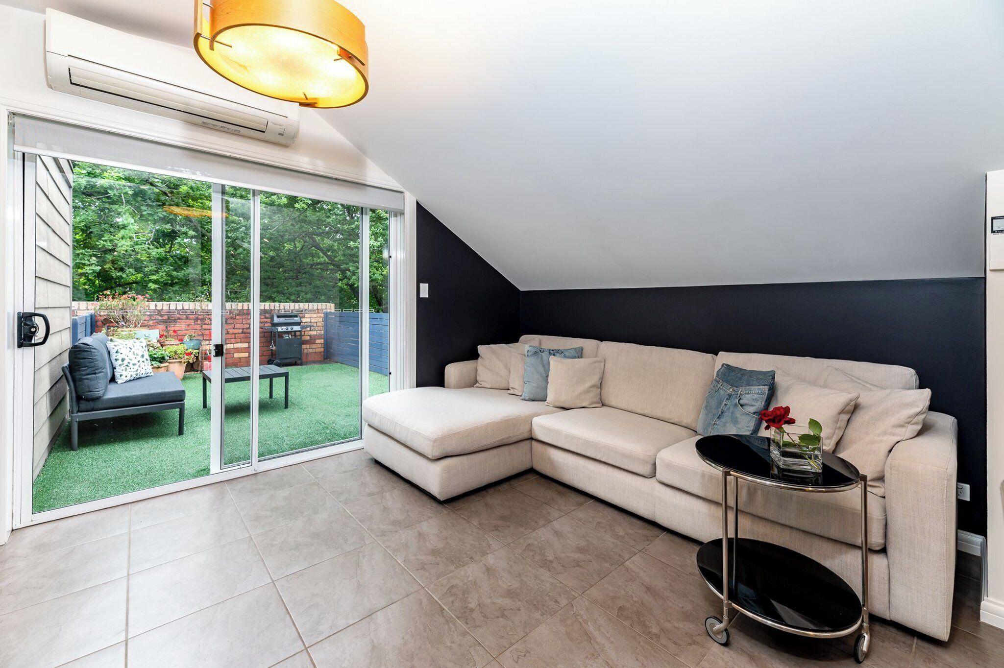 A modern living room with a sectional sofa, a glass door leading to a patio, and a ceiling fan.