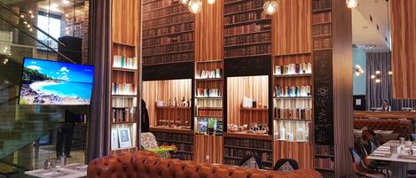 A modern library with bookshelves, a television, and a seating area.