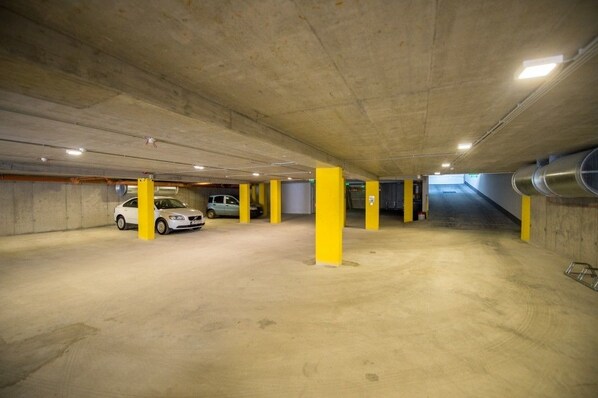 A multi-level underground parking garage with concrete pillars and a few parked cars.
