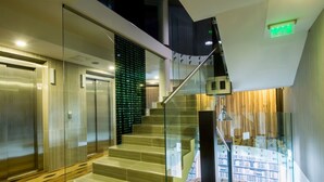 Un intérieur moderne avec un escalier en verre, des ascenseurs et un plancher en bois.