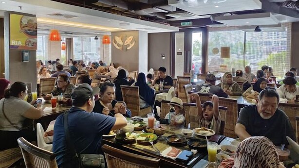 A busy restaurant with multiple tables and patrons. - Ajang Hotel (Miri)
