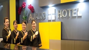 A reception desk at AJANG HOTEL with a modern design, featuring a large sign with the hotel name and decorative flowers. - Ajang Hotel (Miri)