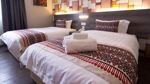A hotel room with two beds, a patterned headboard, a painting on the wall, and a telephone on the nightstand. - Ajang Hotel (Miri)