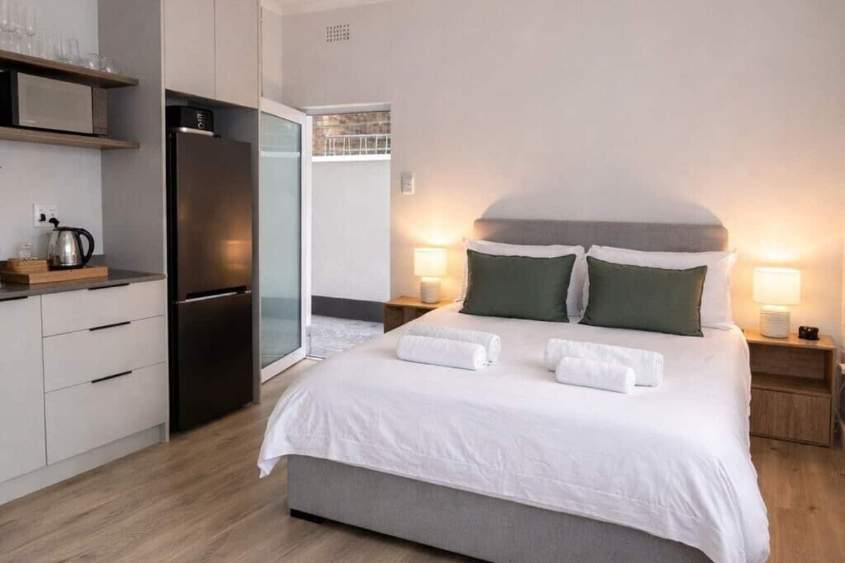 Un dormitorio moderno con cama, mesitas de noche, armario empotrado y zona de cocina.