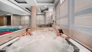 Un área de spa con un jacuzzi, sillones reclinables y una piscina.