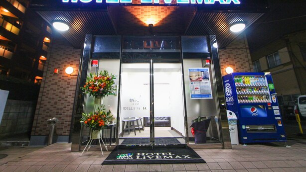 The entrance to Hotel Livemax with a neon sign, a reception desk, and a Pepsi vending machine. - Hotel Livemax Kita Fuchu (Fuchu)