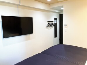 A room with a bed, a mounted television, and a coat rack with hangers. - Hotel Livemax Kita Fuchu (Fuchu)