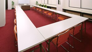 A conference room with a long table, orange chairs, a whiteboard, and a projector screen. - Hotel Livemax Kita Fuchu (Fuchu)