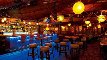 Eine Bar mit Hockern, Tischen und einer Theke.