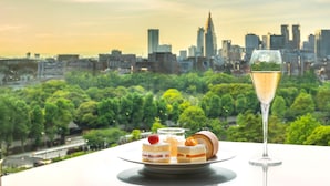 Una mesa con postres y una copa de champán, con vista a un paisaje urbano que destaca un rascacielos.