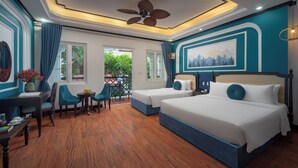 Une chambre avec deux lits, un coin repas comprenant une table et des chaises, un ventilateur de plafond et une vue sur la verdure environnante.