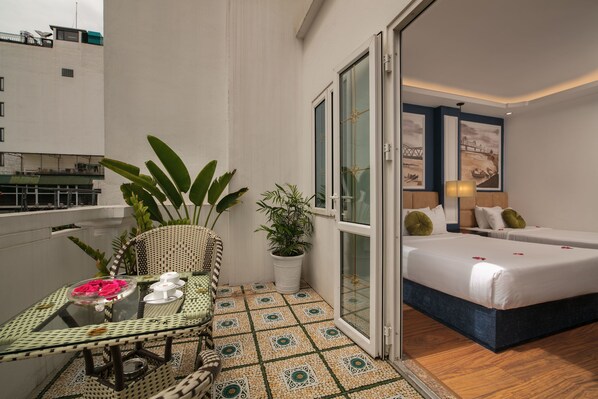 A balcony with a dining table, chairs, and potted plants.