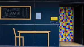 A hostel with a chalkboard displaying room amenities and a colorful mosaic wall. - Hostel and Dining Tanga Table (Kitakyushu)