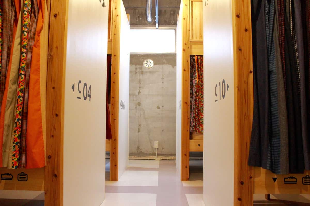 Ein Flur mit Holztüren, die mit Nummern versehen sind, der zu einem Zimmer mit Fenster und Tür führt.