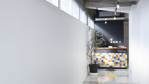 A reception desk with a colorful checkered wall, a potted plant, and a checkered floor. - Hostel and Dining Tanga Table (Kitakyushu)