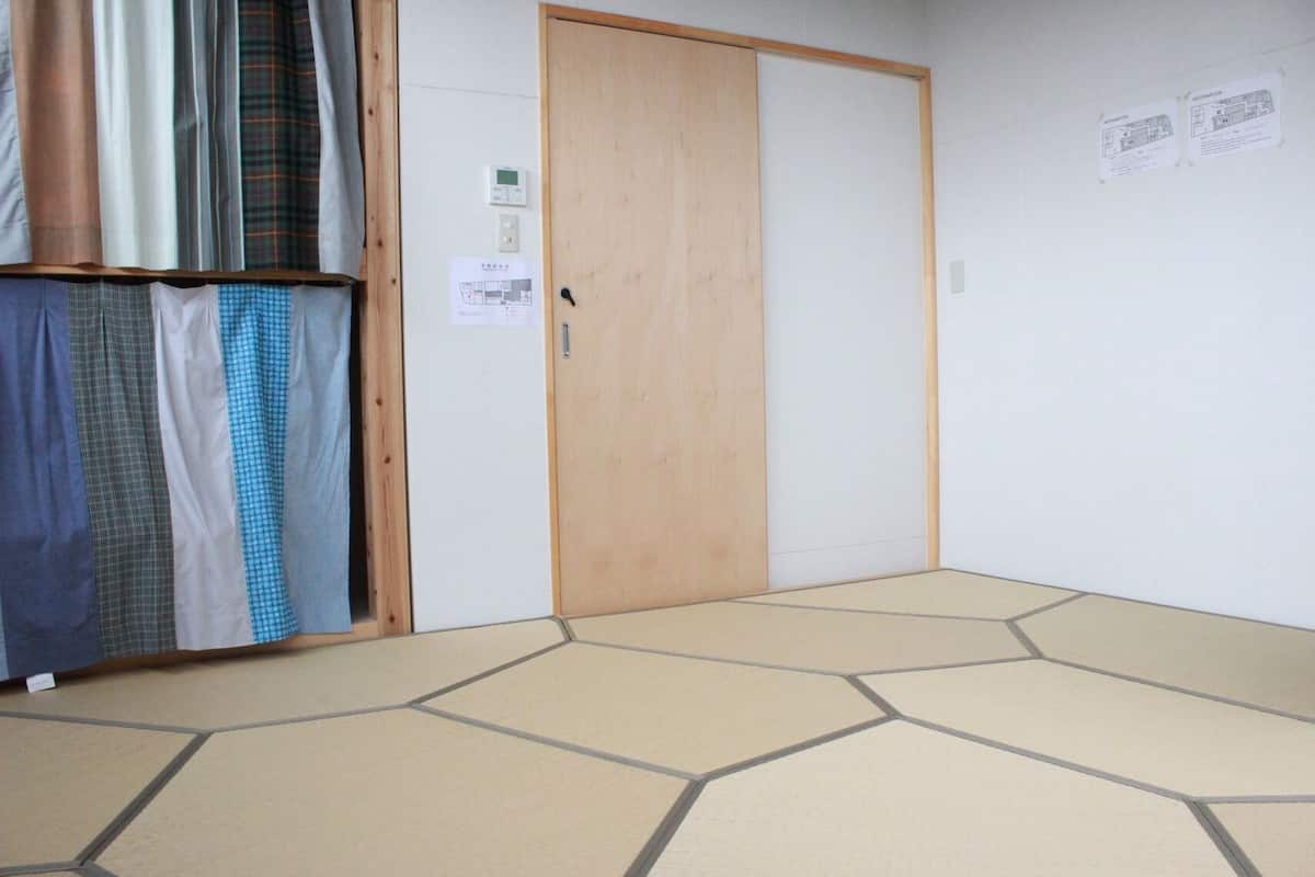 Ein Zimmer mit Holztür, Fliesenboden und einer Wand mit zwei Infografiken.