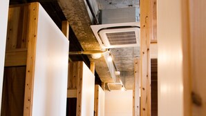 A corridor with wooden beams and white walls, leading to a room with a bed and a window. - Hostel and Dining Tanga Table (Kitakyushu)