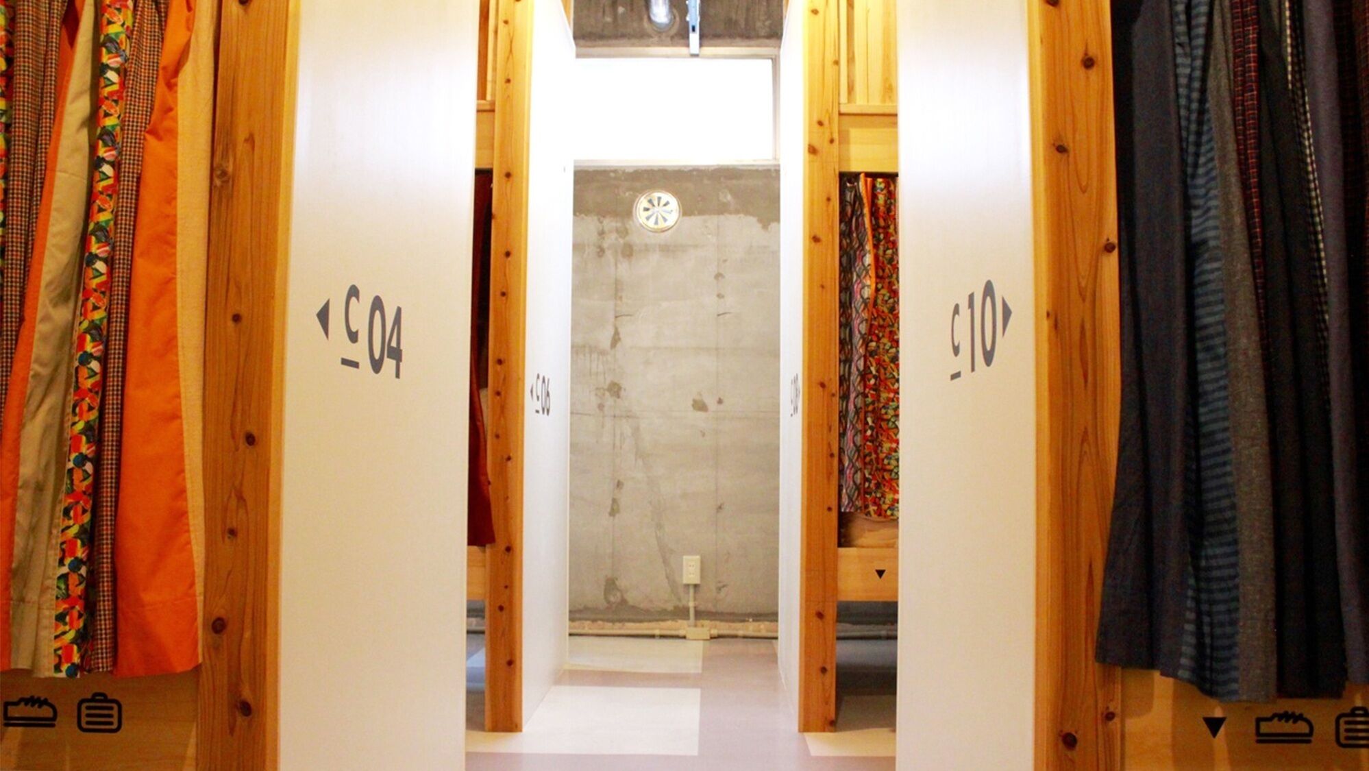 A hallway with wooden doors labeled 'C04' and 'C10' leading to a room with a concrete wall and a small window.