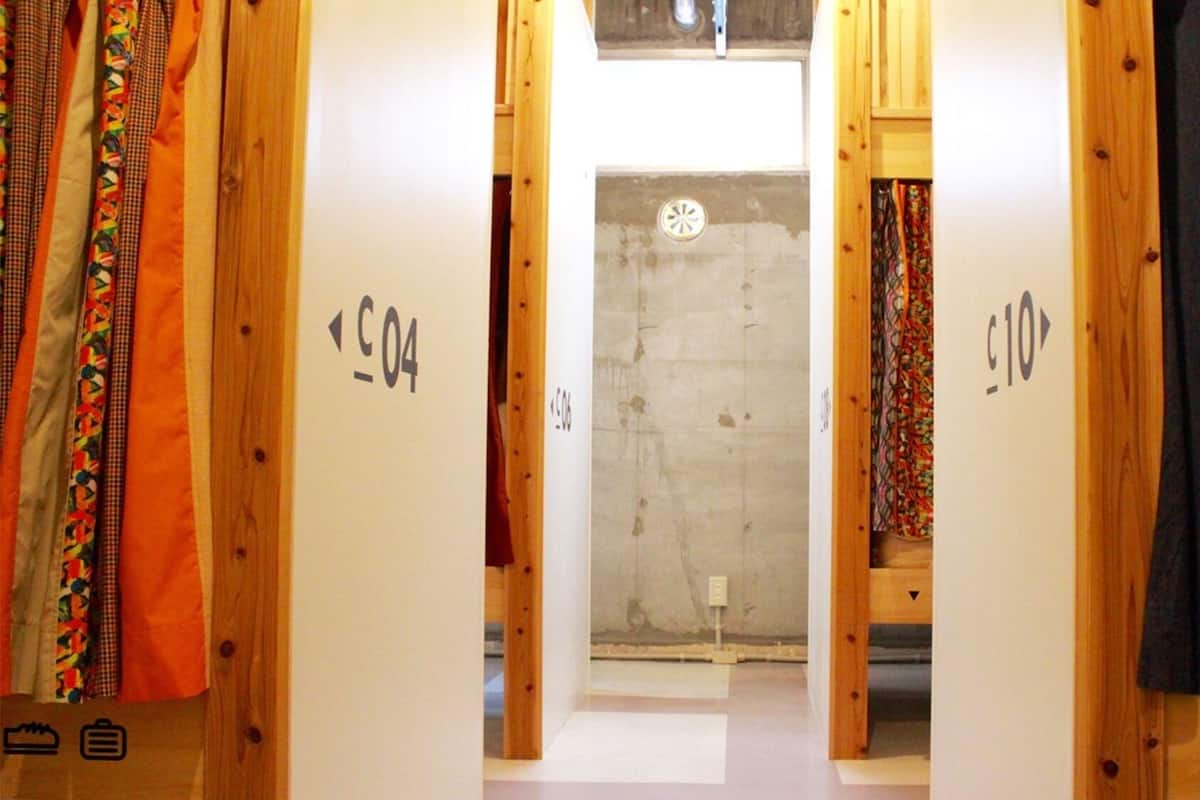 Un couloir avec des portes en bois portant les inscriptions « C04 » et « C10 », qui donnent sur une pièce avec un mur en béton et une petite fenêtre.