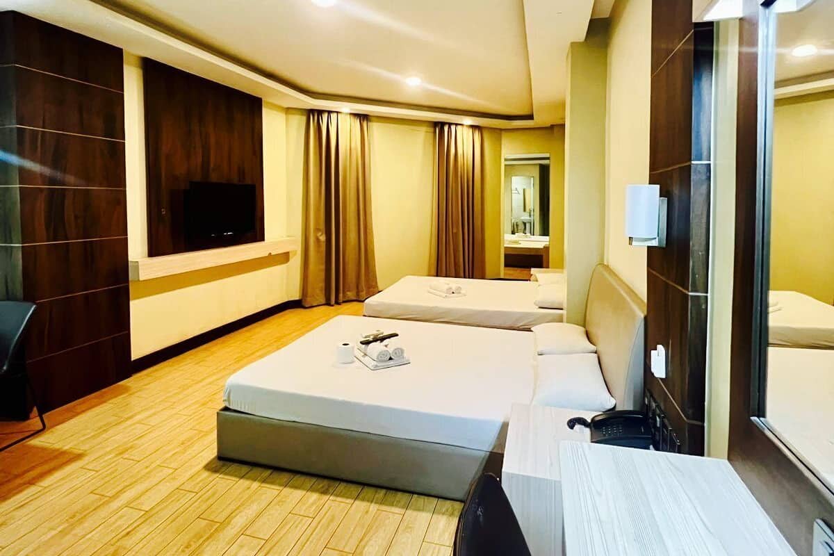 Habitación de hotel con dos camas, un escritorio, una silla, un televisor y un espejo.