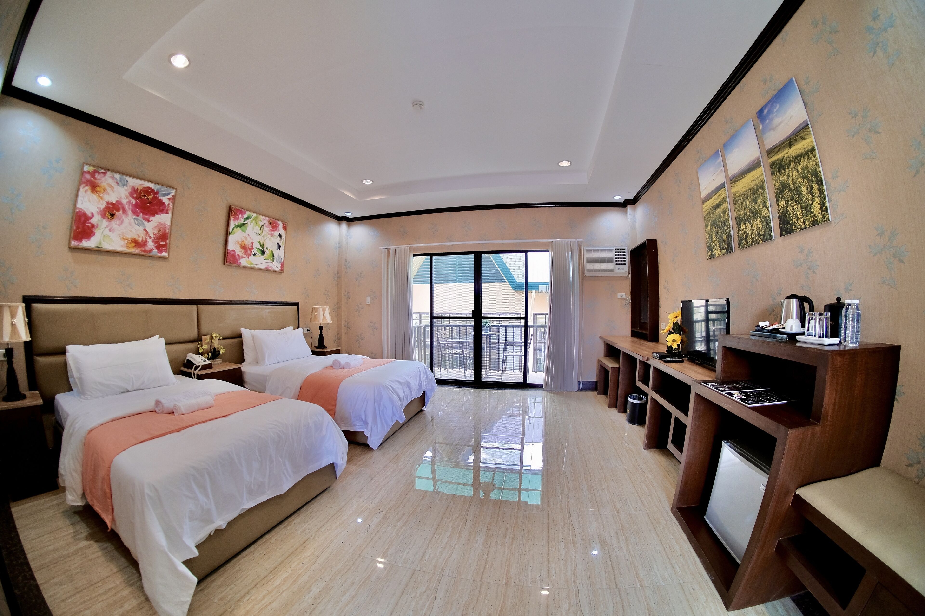 Habitación de hotel con dos camas, un escritorio con ordenador, televisión y balcón con vistas.