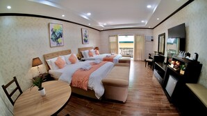 Habitación de hotel con dos camas, una mesa de comedor, un televisor y un balcón con vistas.