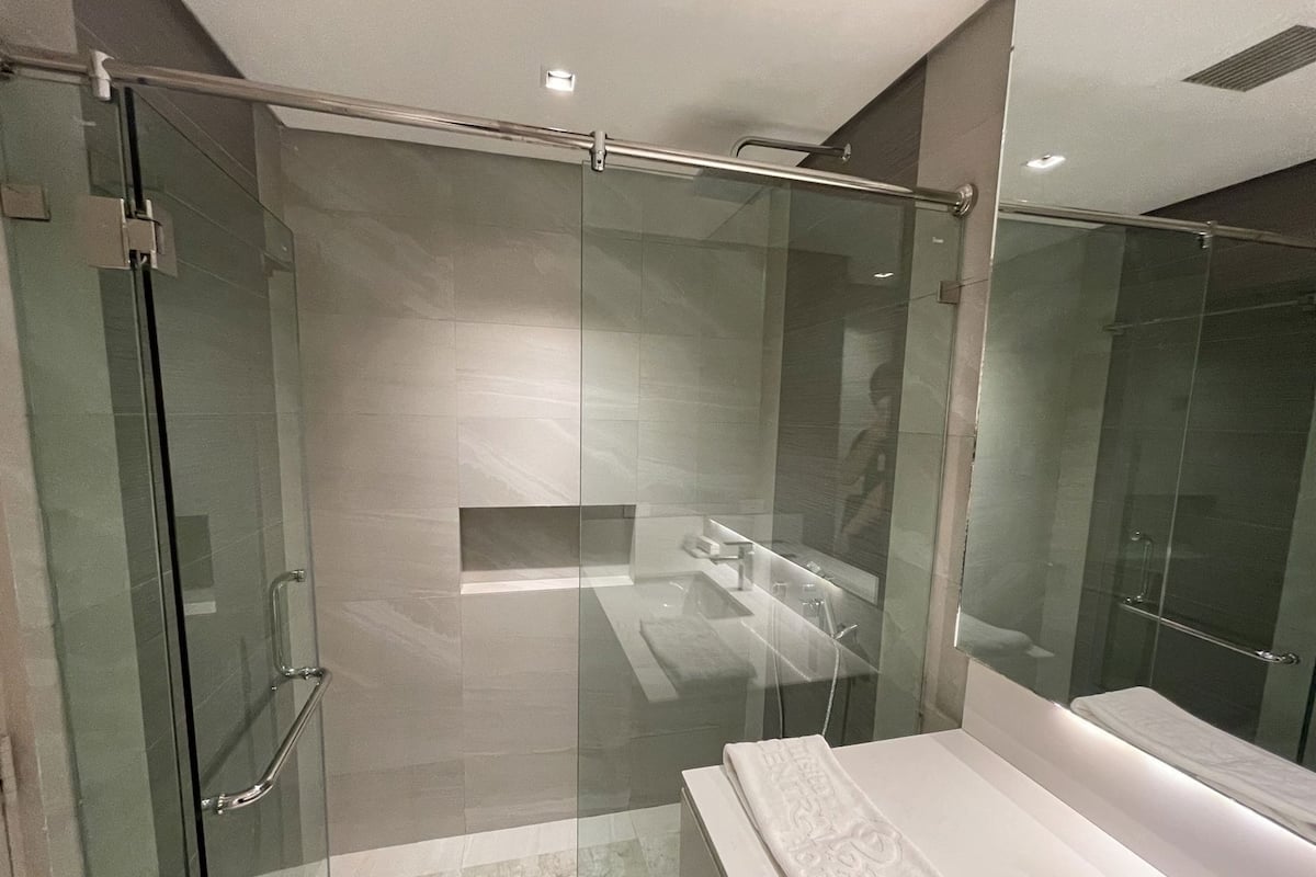 Un baño moderno con cabina de ducha de vidrio, un lavamanos blanco y una toalla en la encimera.