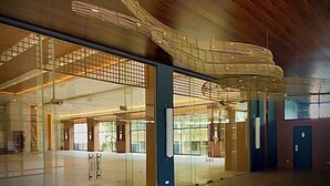 Un vestíbulo amplio con diseño moderno, que destaca por su gran entrada de vidrio, una escalera y una estructura de techo original.