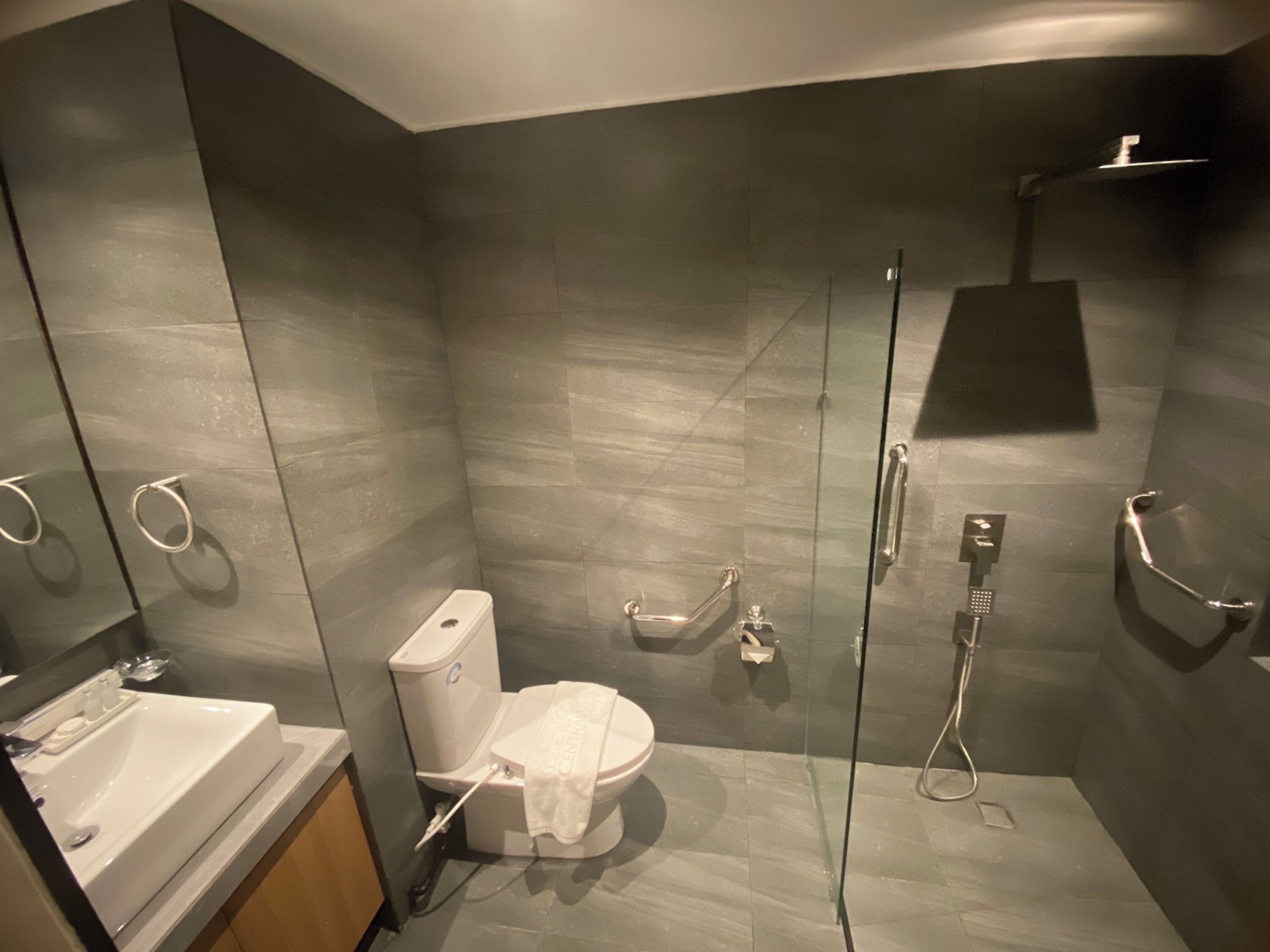 Un baño moderno con ducha de vidrio, inodoro blanco y lavamanos con espejo.