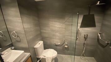 Un baño moderno con ducha de vidrio, inodoro blanco y lavamanos con espejo.