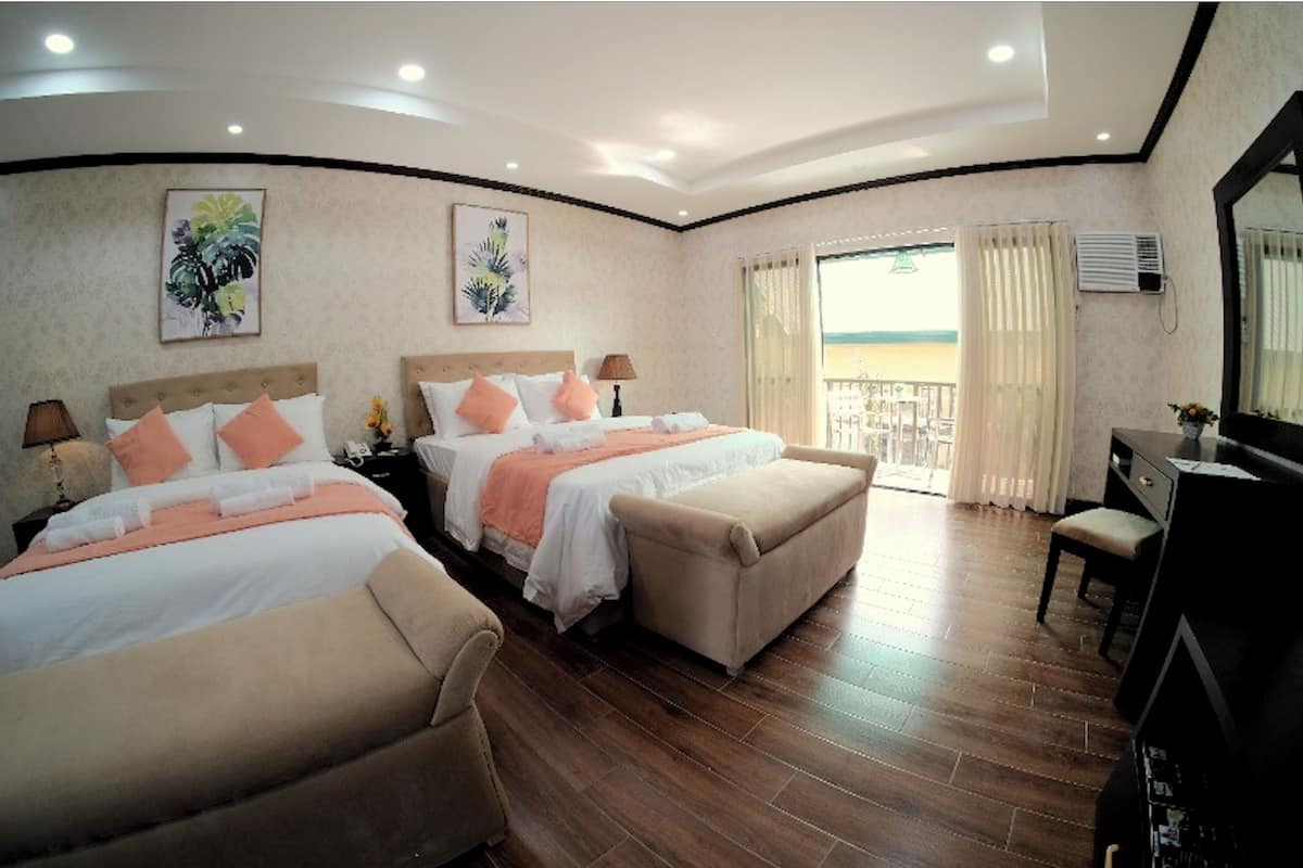 Habitación de hotel con dos camas, un sofá, un escritorio y un balcón con cortinas.