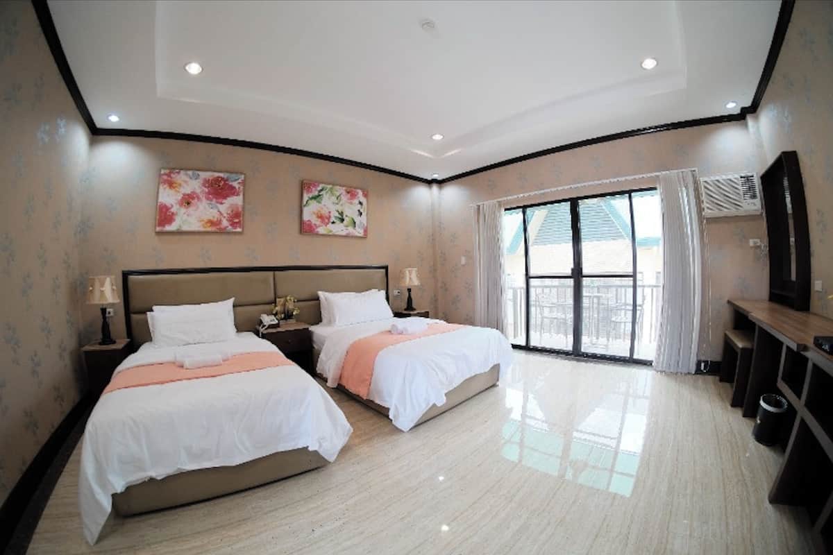 Habitación de hotel con dos camas, un ventanal grande y un balcón.