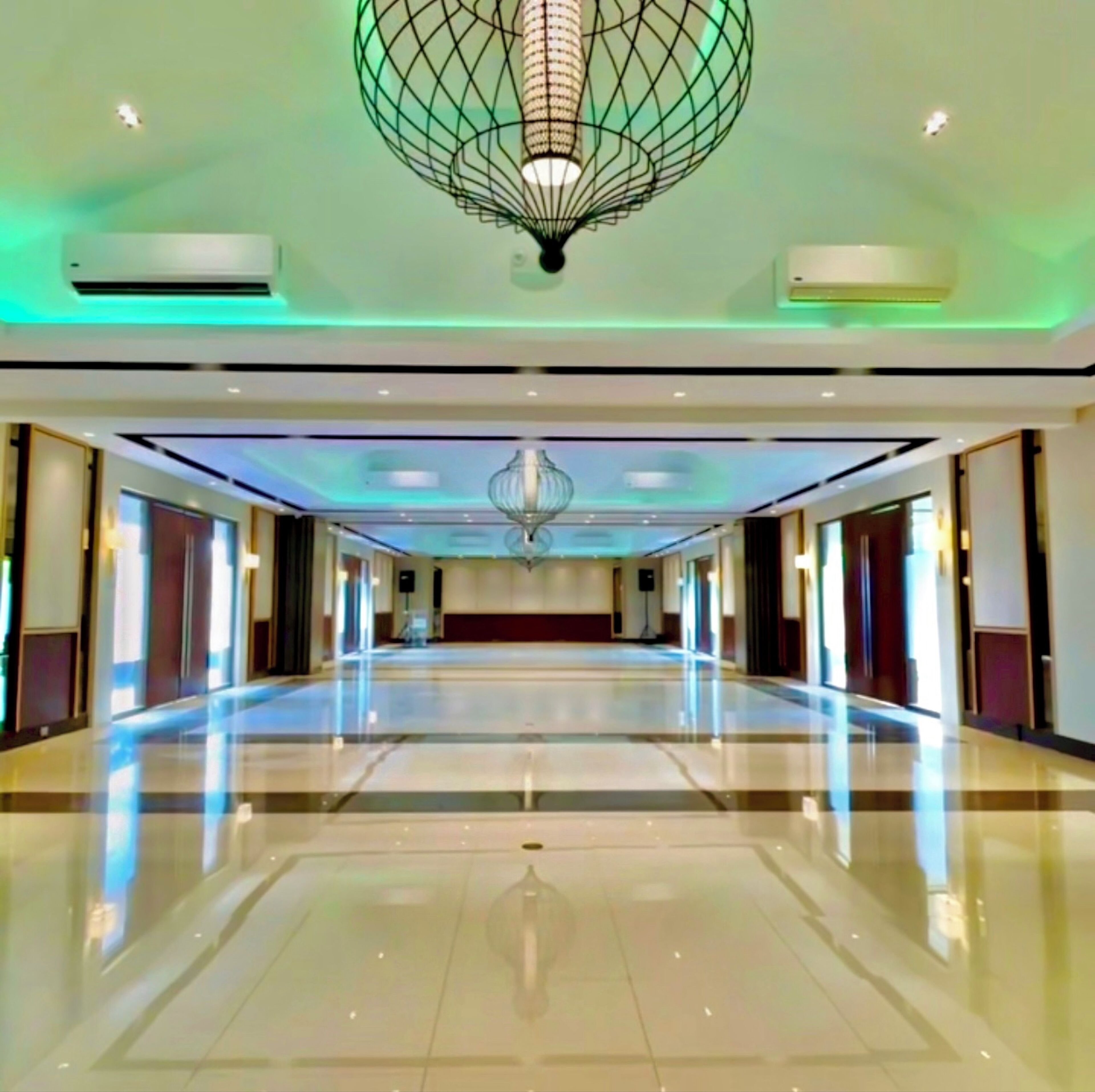 Un amplio vestíbulo de hotel con una gran araña, piso pulido y distribución simétrica.