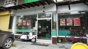 A hotel with a green sign, glass entrance, and a scooter parked outside. - Getz Hotel (Manila)