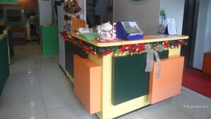 A reception desk at the Getz Hotel with a business permit sign, a directional sign to restrooms, and a Christmas decoration. - Getz Hotel (Manila)