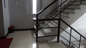 A staircase with a metal railing, a small window, and a red carpet on the floor. - Getz Hotel (Manila)